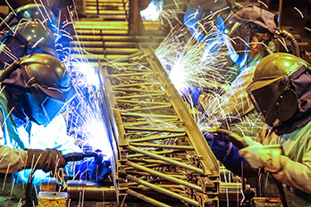 Photo of Nucor teammates welding large piece of steel.